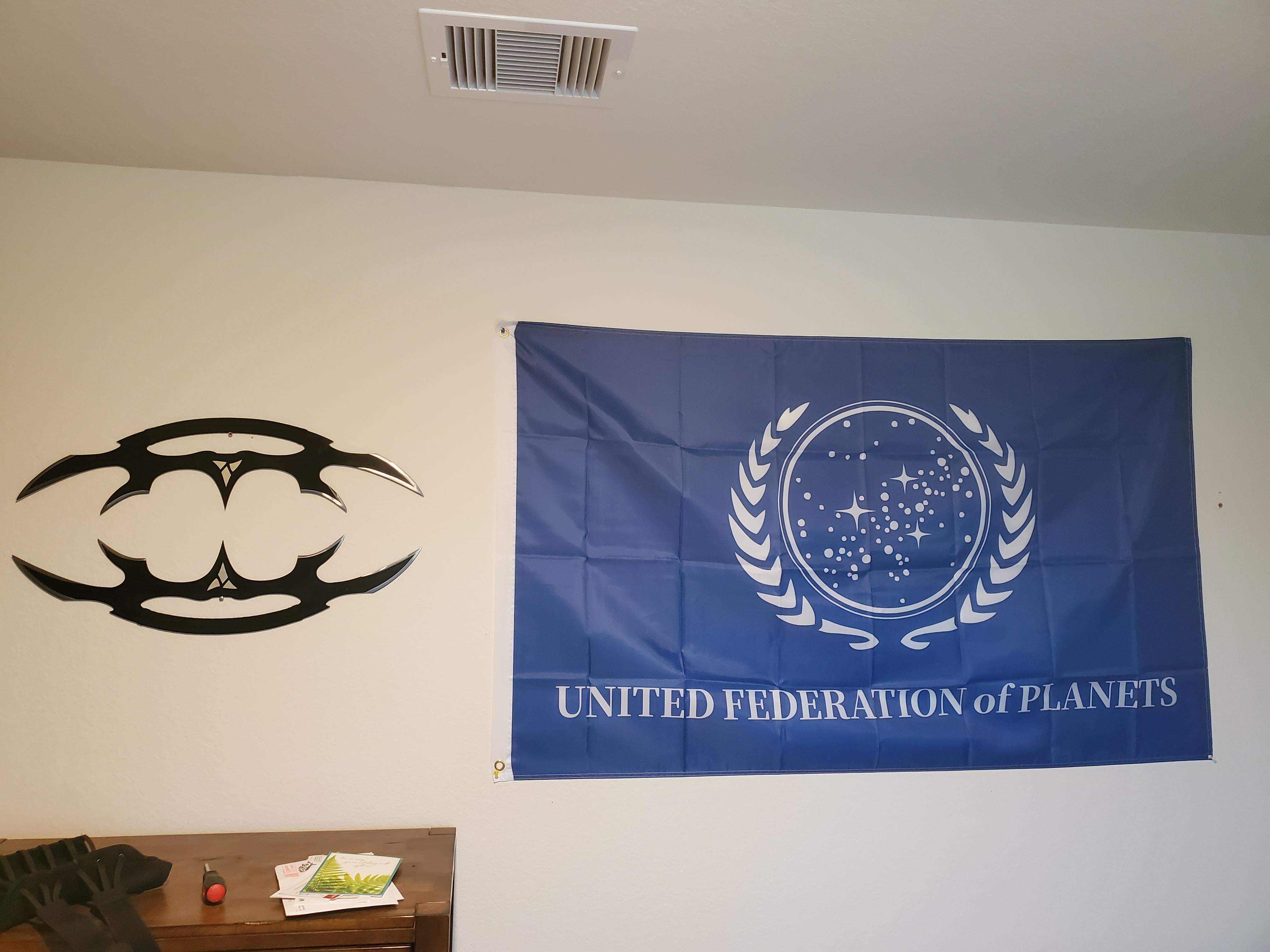 Hanging on the wall, on the right, a Federation flag; on the left, two bat'leths, pointed towards each other, as if to form a circle.
