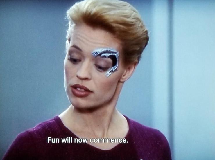 Voyager scene. Seven of Nine (tertiary adjunct of unimatrix 01) is pictured. She has a dolphin shaped metal robotic implant around her left eye because she is a borgs. Closed caption reads, "Fun will now commence."