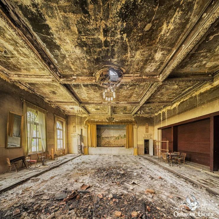 An old ballroom, the stage had mustard colour curtains. The ceiling is burned from a fire