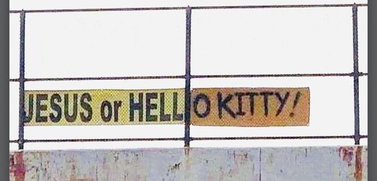 Sign saying "Jesus or Hell" has had an extra piece attached to now read "Jesus or Hello Kitty!".
The extension has a different-coloured background that doesn't really detract from the new message as there's a metal divider between the two that's part of what appears to be a guardrail. 
