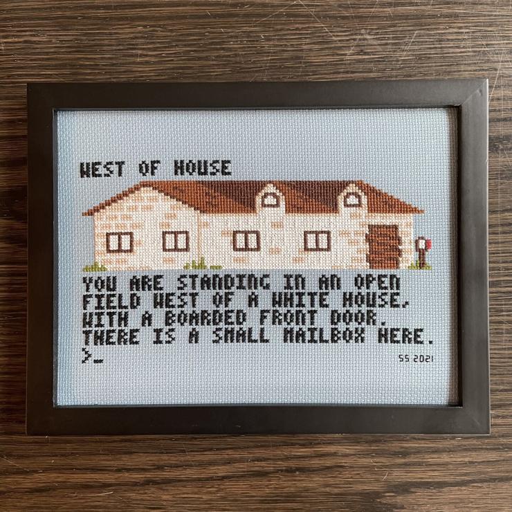 cross stitch picture of a house with the text:
WEST OF HOUSE
YOU ARE STANDING IN AN OPEN FIELD WEST OF A WHITE HOUSE, WITH A BOARDED FRONT DOOR.
THERE IS A SMALL MAILBOX HERE.
>_