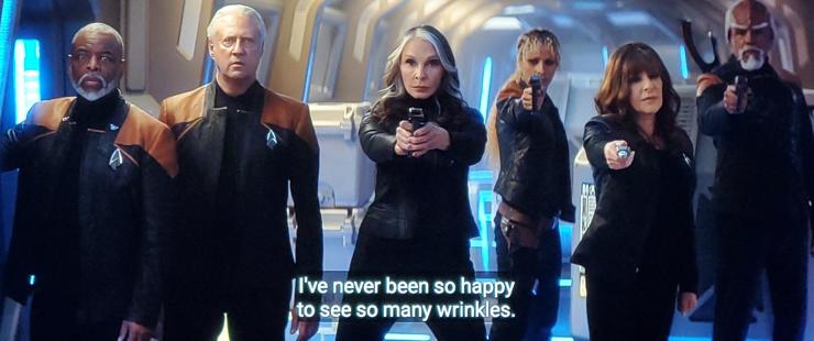 Star Trek Picard screenshot. (Side note, GREAT EPISODE AND SEASON, I don't do a lot of text in my actual tweets and usually try to keep them clean and photo only but man if you're not watching Picard YOURE MISSING OUT FRIENDOS)

Ok, we're in a corridor, and left to right we see Geordi La Forge minus his visor, Data, Beverly Crusher, Rafaella, Deanna Troi, and Worf who is a beautiful Klingon with forehead loaf. They're all either in tactical black or uniform style jackets, all with com badges. Data and Geordi are just standing, the others are holding phasers out in a defensive stance. Closed caption reads, "I've never been so happy to see so many wrinkles."
