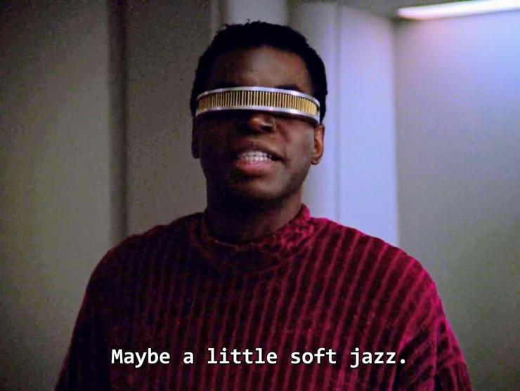 Star Trek The Next Generation scene. Pictured is "After hours Geordi La Forge." He's wearing a velvety cushy soft looking future space guy sweater and he's ready to chillax to the max. Also and always wearing his banana clip looking eye visor. Closed caption reads, "Maybe a little soft jazz."
